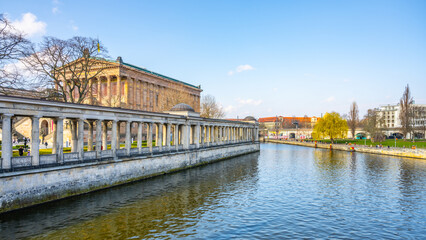 A serene view of the Old National Gallery located along the riverbank in Berlin, with classical...