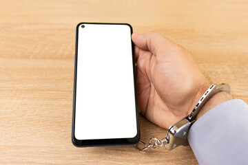 A man in handcuffs is chained to a smartphone. Smartphone addiction concept.