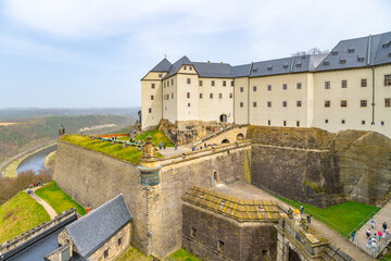 Visitors explore the historic ramparts of Konigstein Fortress in Saxony, under a cloudy sky. Germany