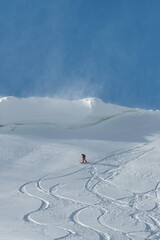 A snowboarder rides under a huge canopy of snow in the mountains