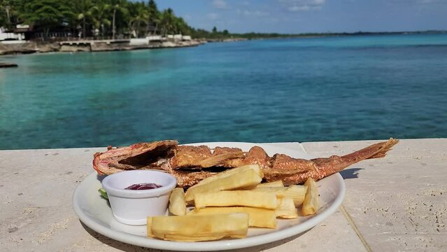 Fried fish as lunch in the beach. Fried fish and yuca ready to eat.