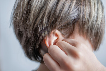 Close-up detail child ear, severe earache, holding onto affected area, experiencing reduced...
