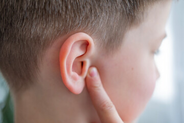 Close-up detail child ear, severe earache, holding onto affected area, experiencing reduced...