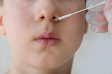 doctor takes cotton bud from child’s nose to analyze the saliva, mucous membrane for DNA tests,...