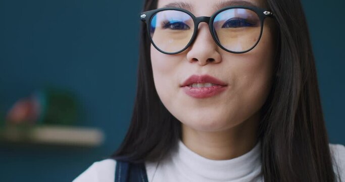 Portrait of Chinese student with glasses for better vision asking question her mentor. Beautiful girl with interesting discussing lesson with her teacher. Taking notes during conversation.