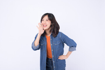 Asian woman wearing orange t shirt and denim jean is posing with a shouting gesture against a white...