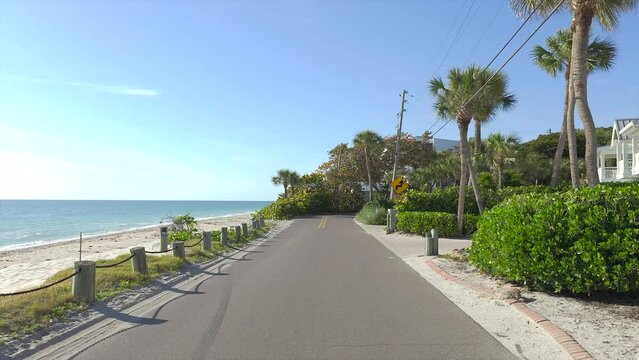 Car point of view driving on scenic road in sunny Florida. Casey Key coastal residential community picturesque streets.