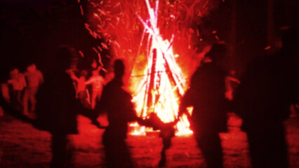 Huge fire at night and young people around. Pagan festival of Walpurgis night: bonfires, dancing...