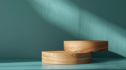 Wooden pedestal platform for product display on a teal background with shadows. Two-tiered wooden pedestal platforms stacked together, bathed in soft light, ideal for showcasing products - 811150483