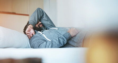Fototapeta premium Tired, sleep and man in bed with stress, burnout and mental health rest in home, apartment or hotel. Fatigue, insomnia and person with depression, anxiety or headache in bedroom to relax in morning