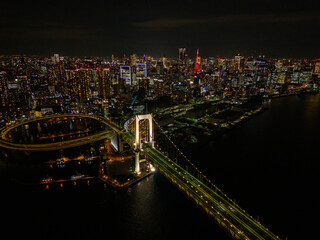 Aerial view of a Rainbow Bridge in Tokyo with evening lights against a background of skyscrapers and lights of moving cars