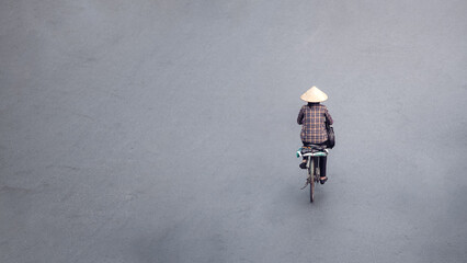 Aerial of a Vietnamese woman rides her bicycle, Hanoi street empty copy space.