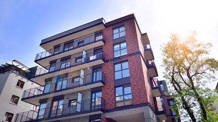 Obraz premium Modern residential building with new apartments in a green residential area. Eco architecture. Green tree and new apartment building. The harmony of nature and modernity.