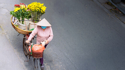 A Vietnamese street vendor woman uses her bicycle to flower stall along a road.