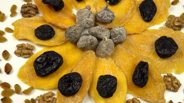 Composition of dried fruits and nuts in the shape of a flower. Dried mango slices, prunes and figs, raisins and peeled walnut kernels, natural background, top view