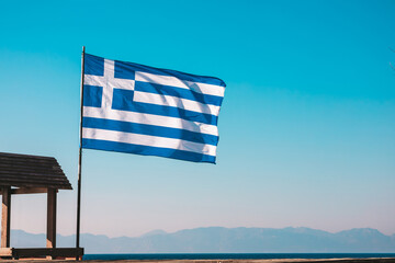 The national flag of Greece against the sky and mountains. Greece Independence Day. Waving Greek...