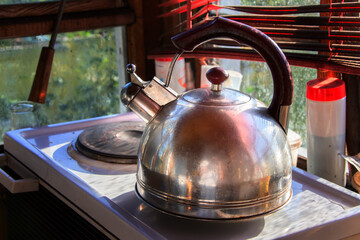 An antique metal teapot with a whistle on the stove in an everyday setting.