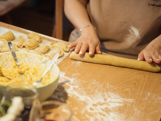 A horizontal close-up captures a woman making dumplings, as she skillfully shapes dough with a...