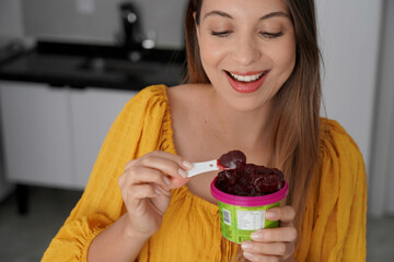 Latin American young woman eating acai sorbet ice cream frozen dessert at home