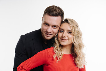 Obraz premium A man and woman are posing for a picture in red. The man is wearing a black suit and the woman is wearing a red shirt.
