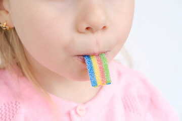 child, girl 4 years old enjoys gelatinous sweets, colorful rainbow sugar marmalade, happy...