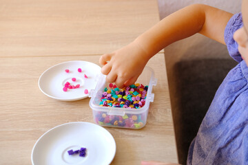 smart small child, toddler counts, sorts small plastic chips color, kid's fingers closeup,...
