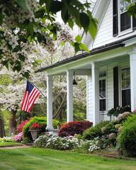 Fototapeta na wymiar American flag on the porch of a house with blooming cherry trees