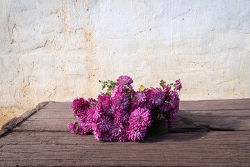 Bodegón rustico o adorno floral con mesa de madera y flores rojas.