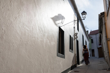 Una mujer turista camina por una soleada callejuela de un pueblo andaluz.
