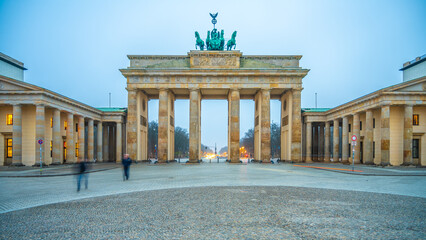 Twilight descends on Brandenburg Gate, with soft lighting illuminating the historic arch and the...