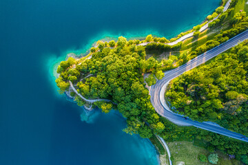 Aerial View of Lago di Ledro with Turquoise Water and Winding Road, Vibrant Summer Landscape in...
