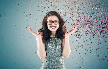 Happy, celebration and woman on blue background with confetti for success, winning and birthday surprise. Winner, excited and isolated person with glitter for party, prize and achievement in studio