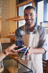 Man, cashier and smartphone for pos in coffee shop, ecommerce and transaction on electronic...