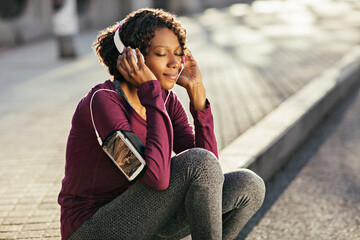 Young African American woman listening to music in urban setting