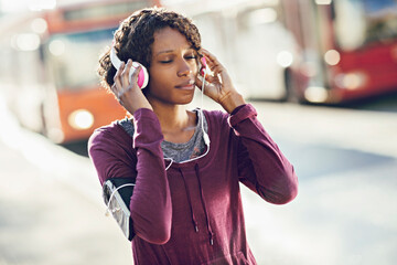 Smiling young active woman with headphones outdoors in city