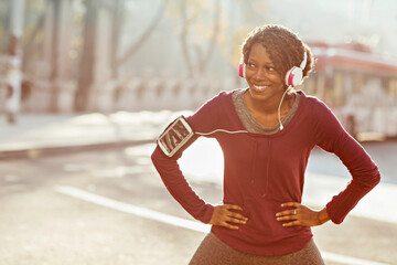 Smiling young active woman with headphones outdoors in city