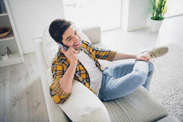 Photo of funky positive man wear checkered shirt staying home listening modern device indoors house...