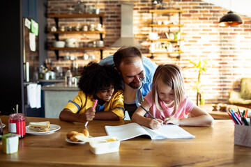 Father helping children with homework at kitchen table