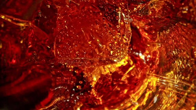Super Slow Motion of Falling Ice Cube into Cola Drink. Filmed on High Speed Cinema Camera, 1000 fps, Camera Tracking the Target.