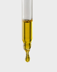 Cosmetic pipette with a drop close-up on a gray background