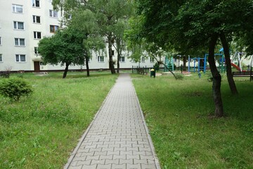 A sidewalk running through an estate with old blocks of flats