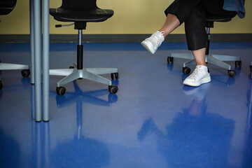 Feet in white sneakers under the table, classroom, advanced training courses for adults