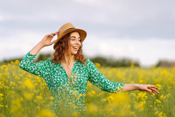 Beautiful woman walks run along yellow field rapeseed. Nature, fashion, summer lifestyle.