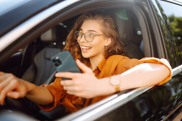 Young woman texting on her smartphone while driving a car. Car sharing, rental service or taxi app....