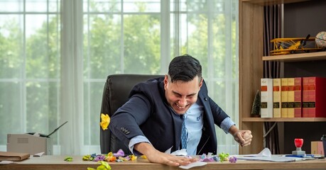 A man in a suit is throwing things around in his office. He looks very angry.