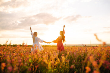 Two Beautiful women in the blooming field at sunset. Nature, vacation, relax and lifestyle. Summer...