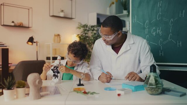 Boy and father in lab coats, goggles play scientists, exploring chemistry