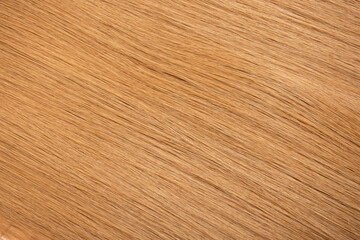 Obraz premium Red hair close-up as a background. Women's long orange hair. Beautifully styled wavy shiny curls. Hair coloring bright shades. Hairdressing procedures, extension.