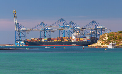 Large container ship being loaded at the cargo port of Malta.