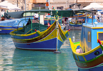 Multi-colored fishing boats luzzi with eyes in the harbor of the village Marsaxlokk on the island...
